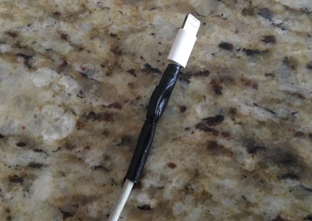 Un caricabatterie iPhone rotto riparato temporaneamente fissato con nastro isolante